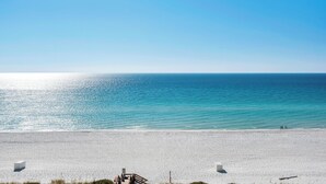 A beach with a wooden walkway leading to the water, a sandy beach, and a clear blue sky.