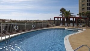 A swimming pool with a pergola and palm trees in the background.