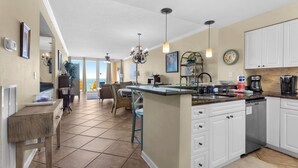 A spacious kitchen with a large island, white cabinetry, and a view to the outside.