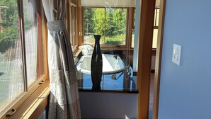 A narrow hallway with wooden flooring, a window with curtains, and a view of a boat outside. - Admiral's Suite - Spacious, Flagship Condo as you enter Eastsound (Eastsound)