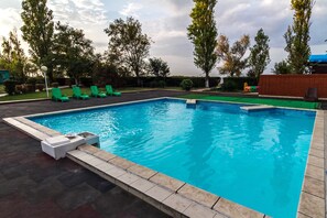 Relax by the pool surrounded by lush greenery and comfortable lounge chairs.