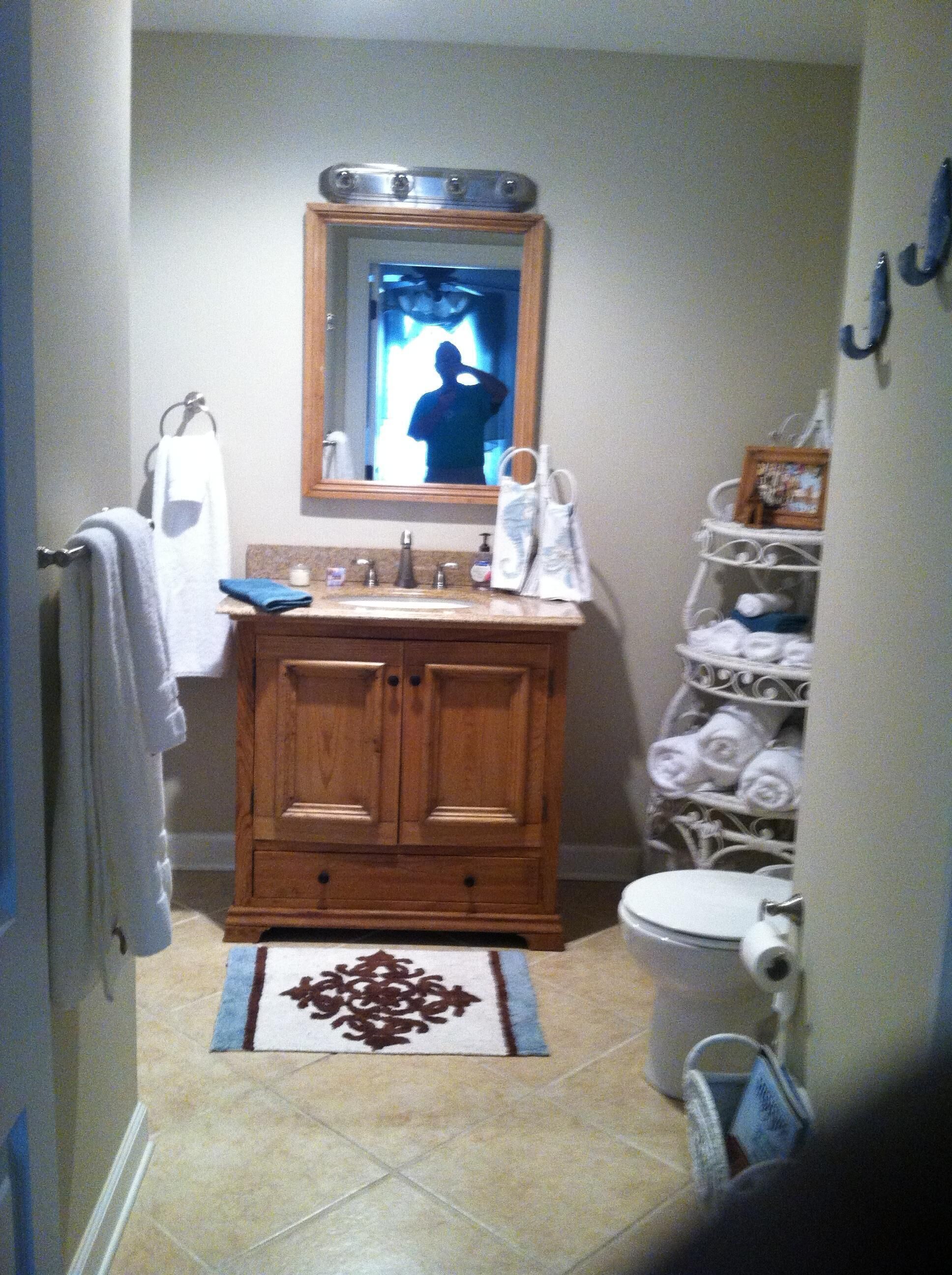 Een badkamer met een houten wastafelmeubel, een wastafel, een spiegel, een toilet en een handdoekhouder.