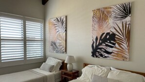 Une chambre d’hôtel avec deux lits, une table de chevet avec une lampe et des œuvres d’art accrochées aux murs.