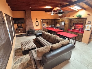 Un espacio de sala acogedor con chimenea, un sofá y una cocina con encimeras rojas.
