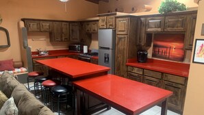 A kitchen with wooden cabinets, a red countertop, a refrigerator, a stove, and a coffee maker. - Casita Calypsito, Playa Dorada / Beachfront Beauty! (Playa Dorada)