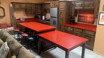 A kitchen with wooden cabinets, a red countertop, a refrigerator, a stove, and a coffee maker.
