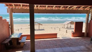 A beachside patio with a view of the ocean, featuring a tiled floor, wooden benches, and a pergola with a tiled roof. - Casita Calypsito, Playa Dorada / Beachfront Beauty! (Playa Dorada)