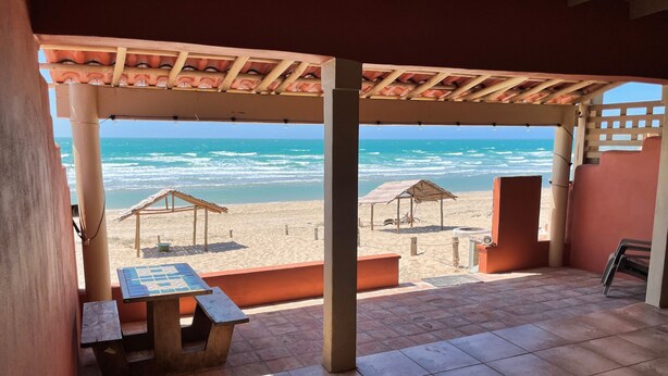 A beachside patio with a table and chairs, overlooking the ocean. - Casita Calypsito, Playa Dorada / Beachfront Beauty! (Playa Dorada)