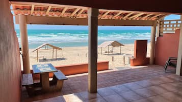 A beachside patio with a table and chairs, overlooking the ocean.
