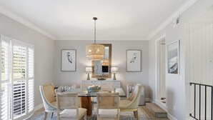 Comedor con candelabro, obras de arte enmarcadas y vista al exterior.