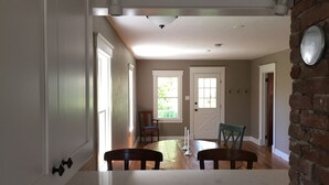 A spacious kitchen with a large island, wooden chairs, and a dining table. - Fully Renovated Old Town Cottage Close to Downtown, City Park, and University  (Fort Collins)