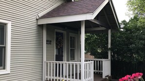 A two-story house with a covered porch and a garden with flowers. - Fully Renovated Old Town Cottage Close to Downtown, City Park, and University  (Fort Collins)