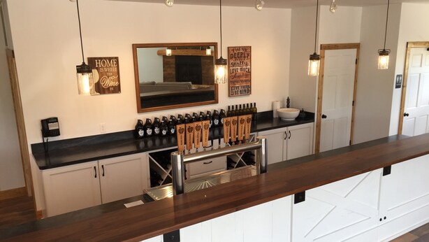 Un espace bar doté d’un long comptoir, d’une cave à vin et d’un miroir placé au-dessus du comptoir.