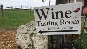 Panneau indiquant un espace de dégustation de vins et un bar proposant du cidre artisanal à la pression.