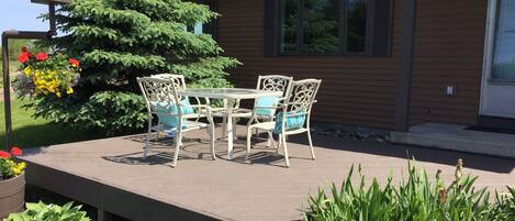 A patio with a table and chairs, surrounded by plants and a large tree.
