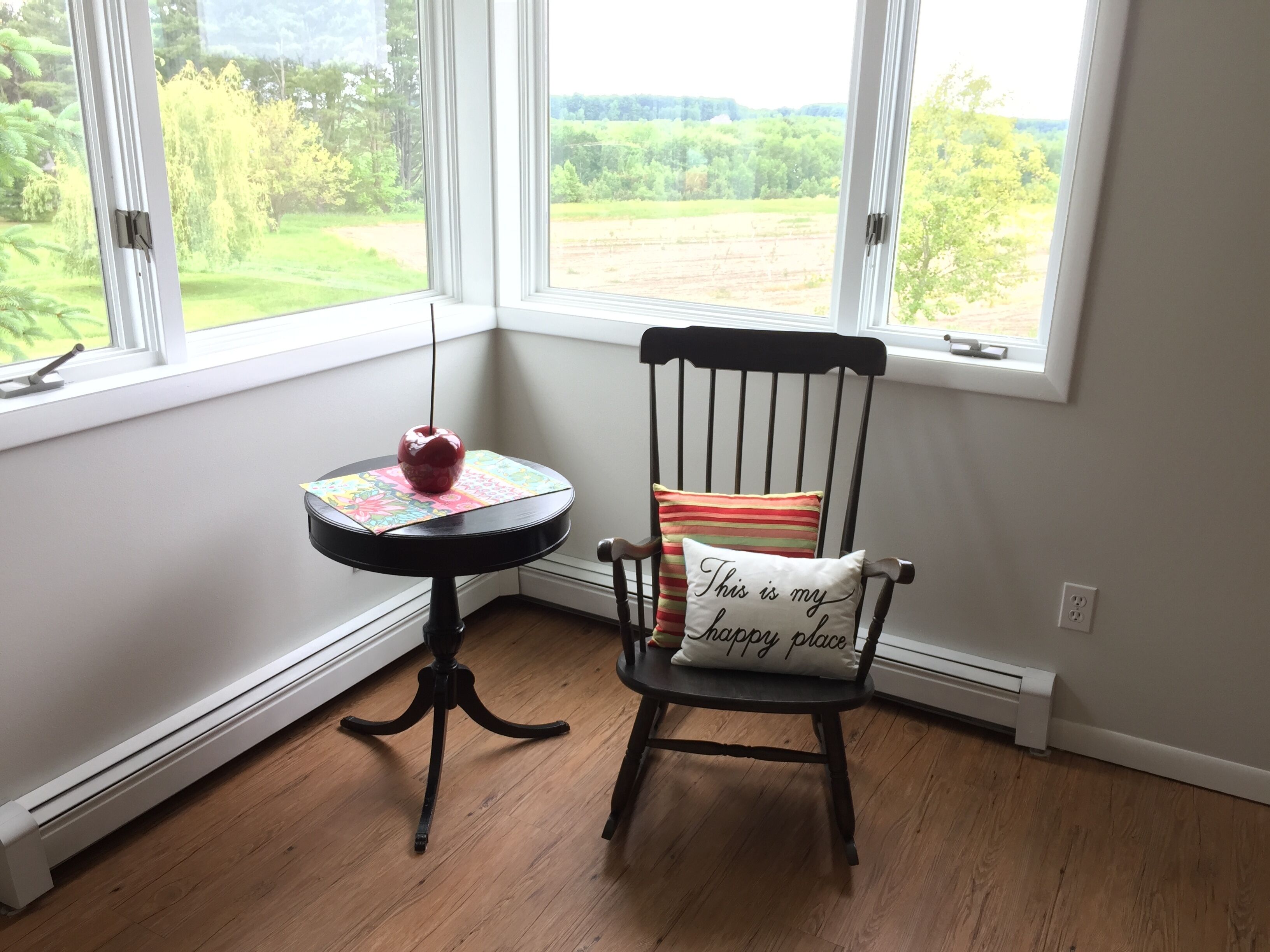 A corner room with a wooden chair and a small table with a red apple.