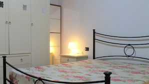 A bedroom with a bed, a nightstand, a lamp, and a wardrobe. - Casa Violetta (Portoferraio)