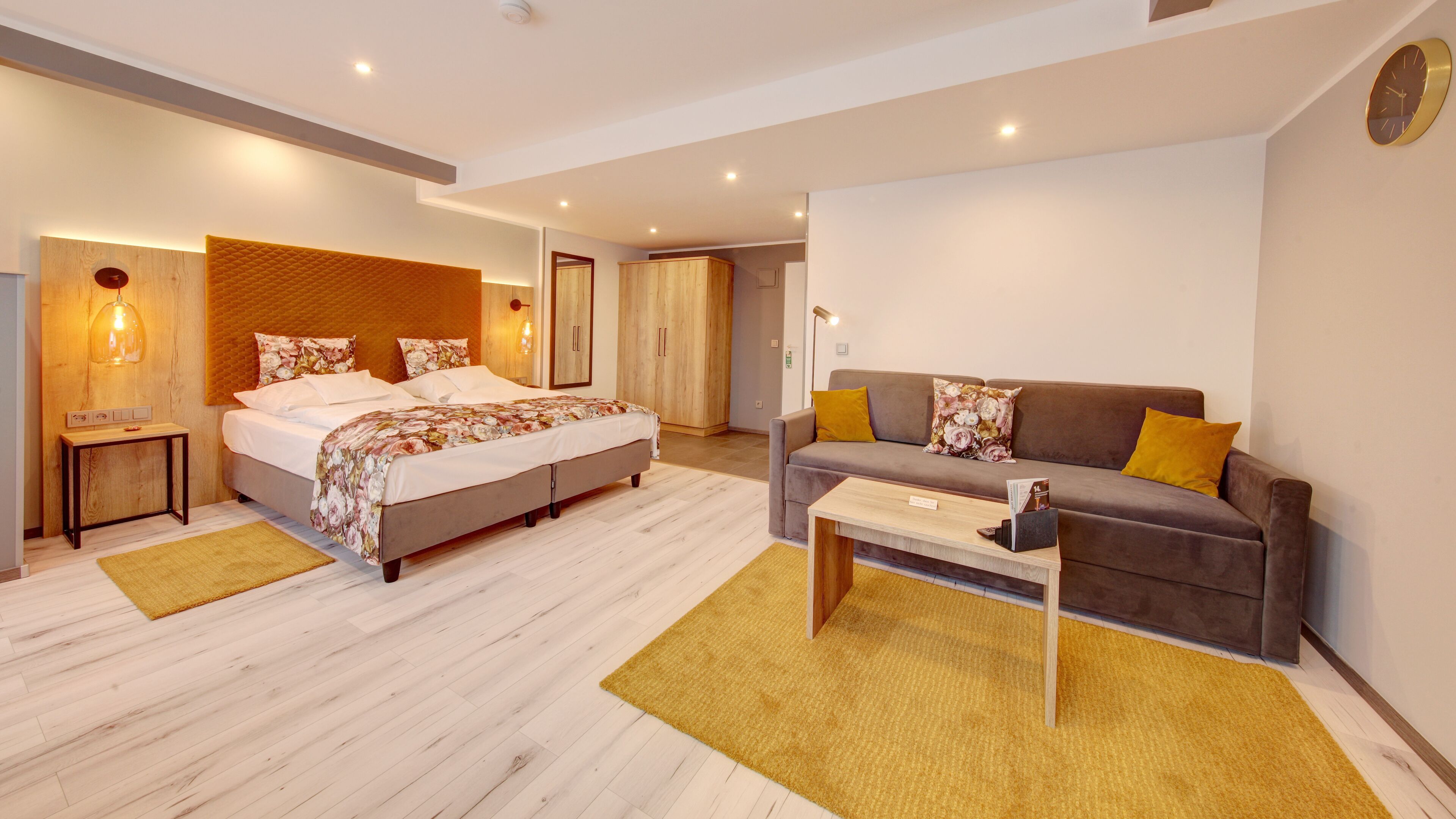 Quarto de hotel moderno com uma cama, um sofá, uma mesa de centro e uma mesinha de cabeceira com abajur.