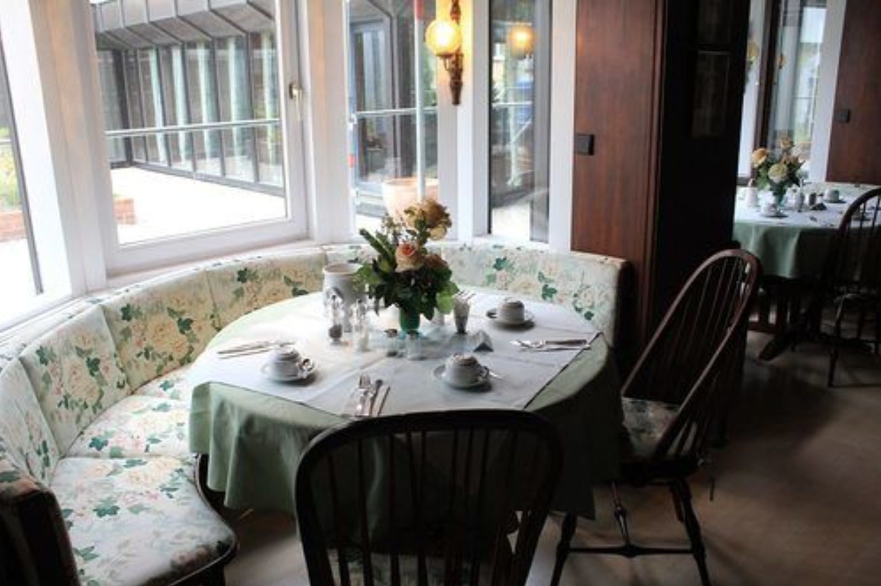 Un coin repas avec une table ronde dressée pour deux personnes, entourée de chaises ornées de motifs floraux.