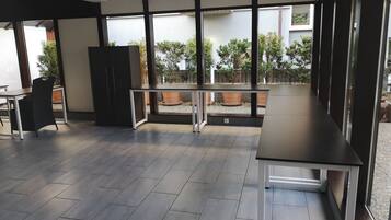 A modern kitchen with dark wooden flooring, a black countertop, and a window overlooking a garden.
