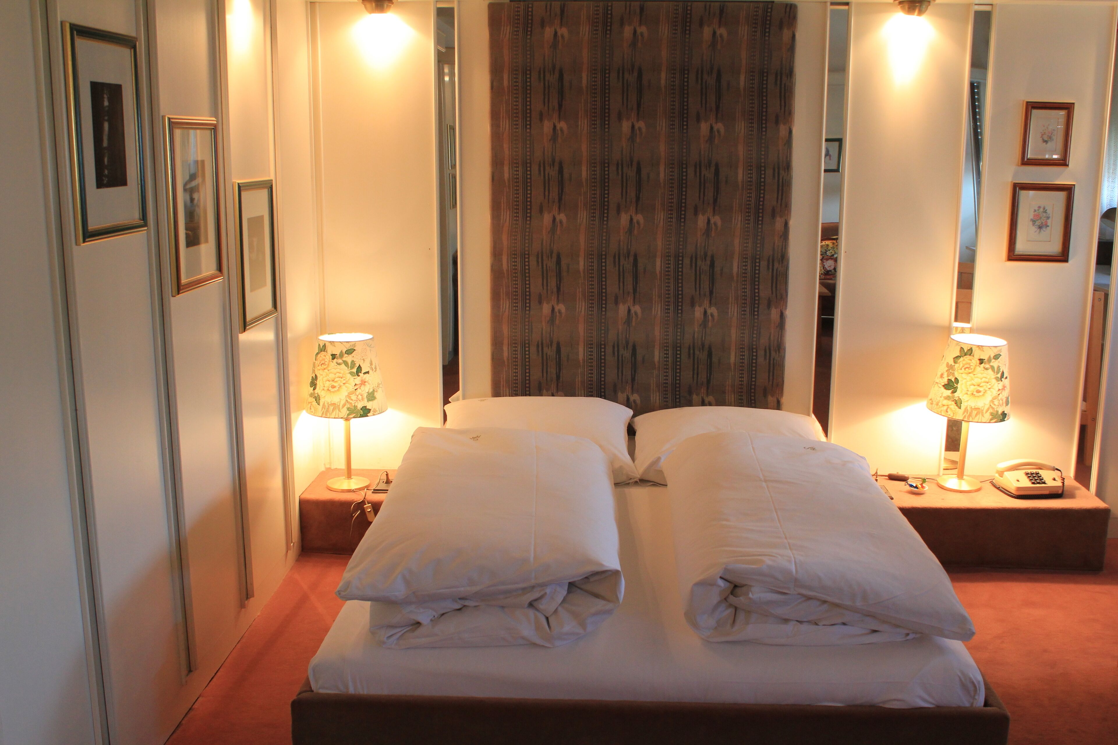 A hotel room with a large bed, two bedside tables, and a mirror on the wall.