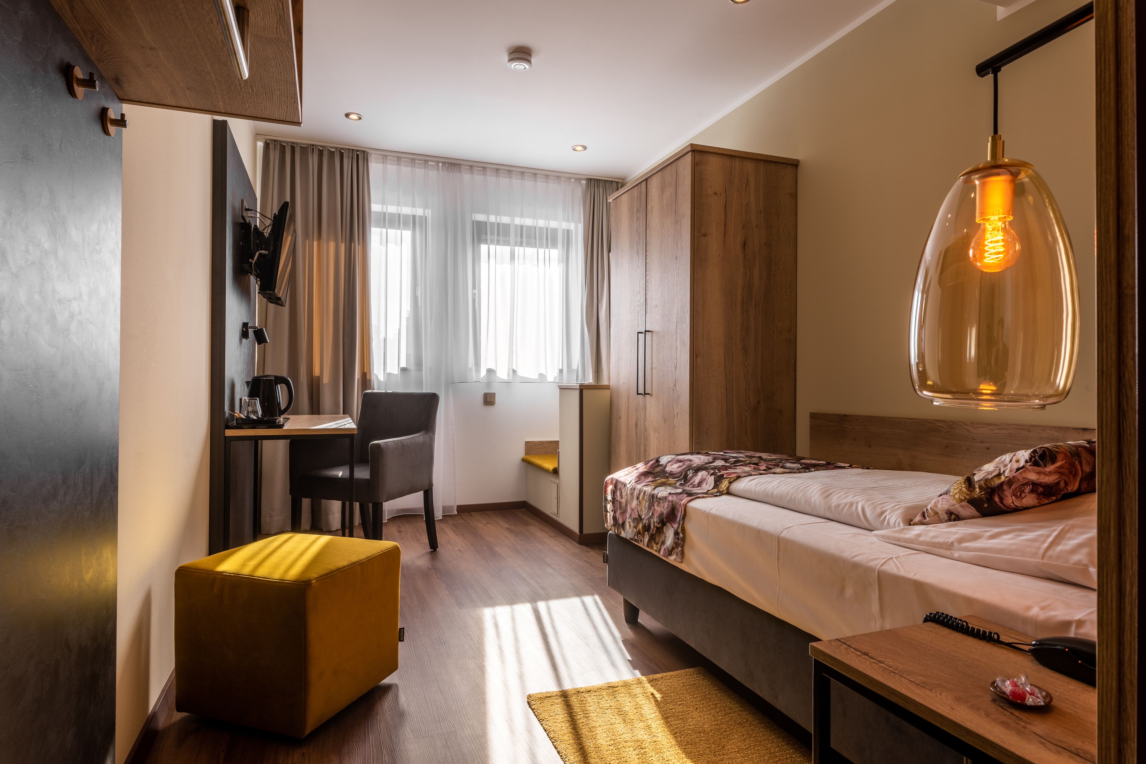 A compact hotel room with a bed, a desk, and a chair.