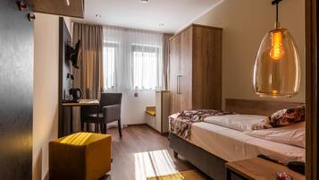 A compact hotel room with a bed, a desk, and a chair.