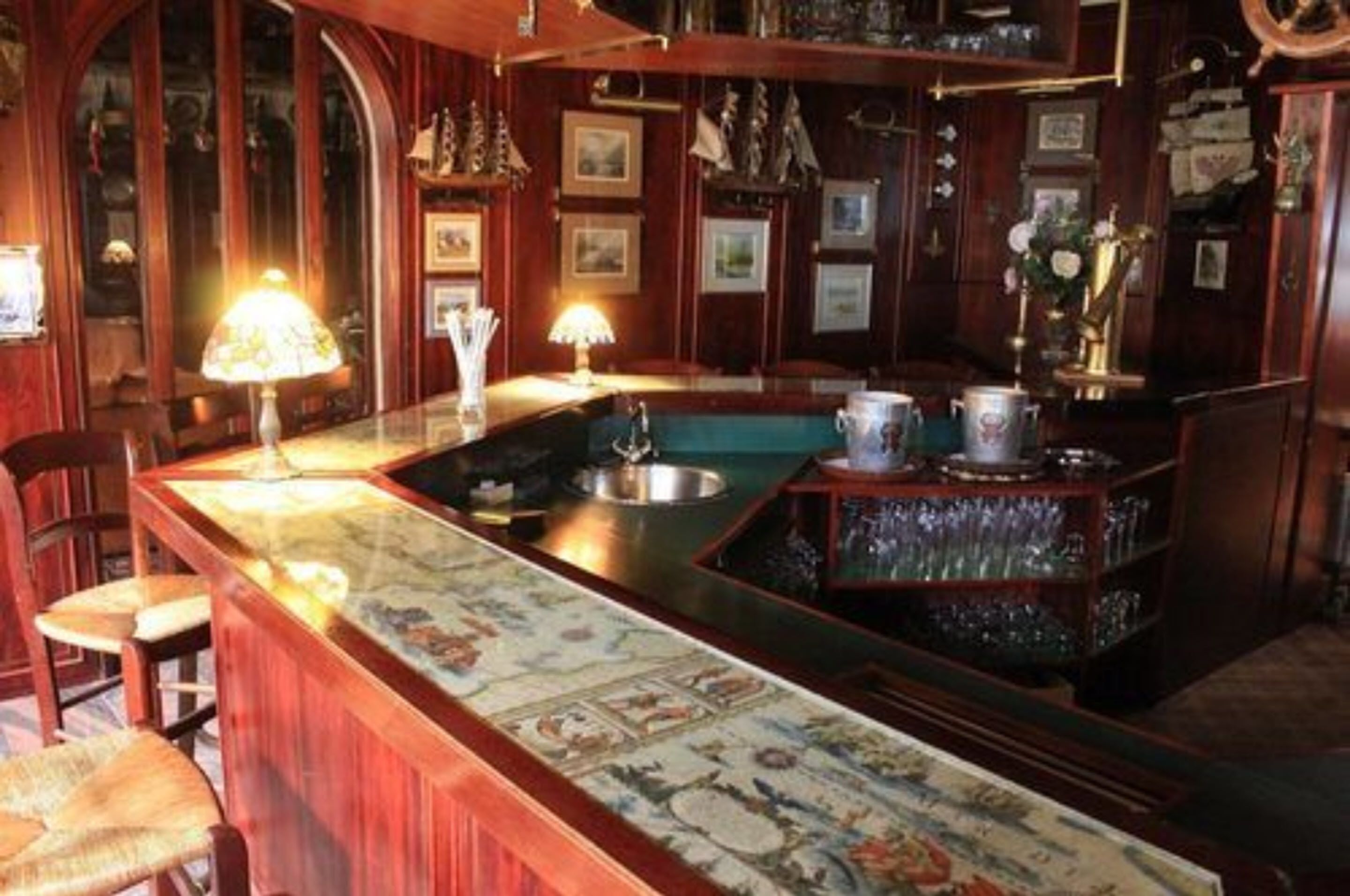 Una zona de bar con mostrador de madera, taburetes y una alfombra decorativa.