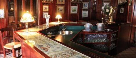 Una zona de bar con mostrador de madera, taburetes y una alfombra decorativa.