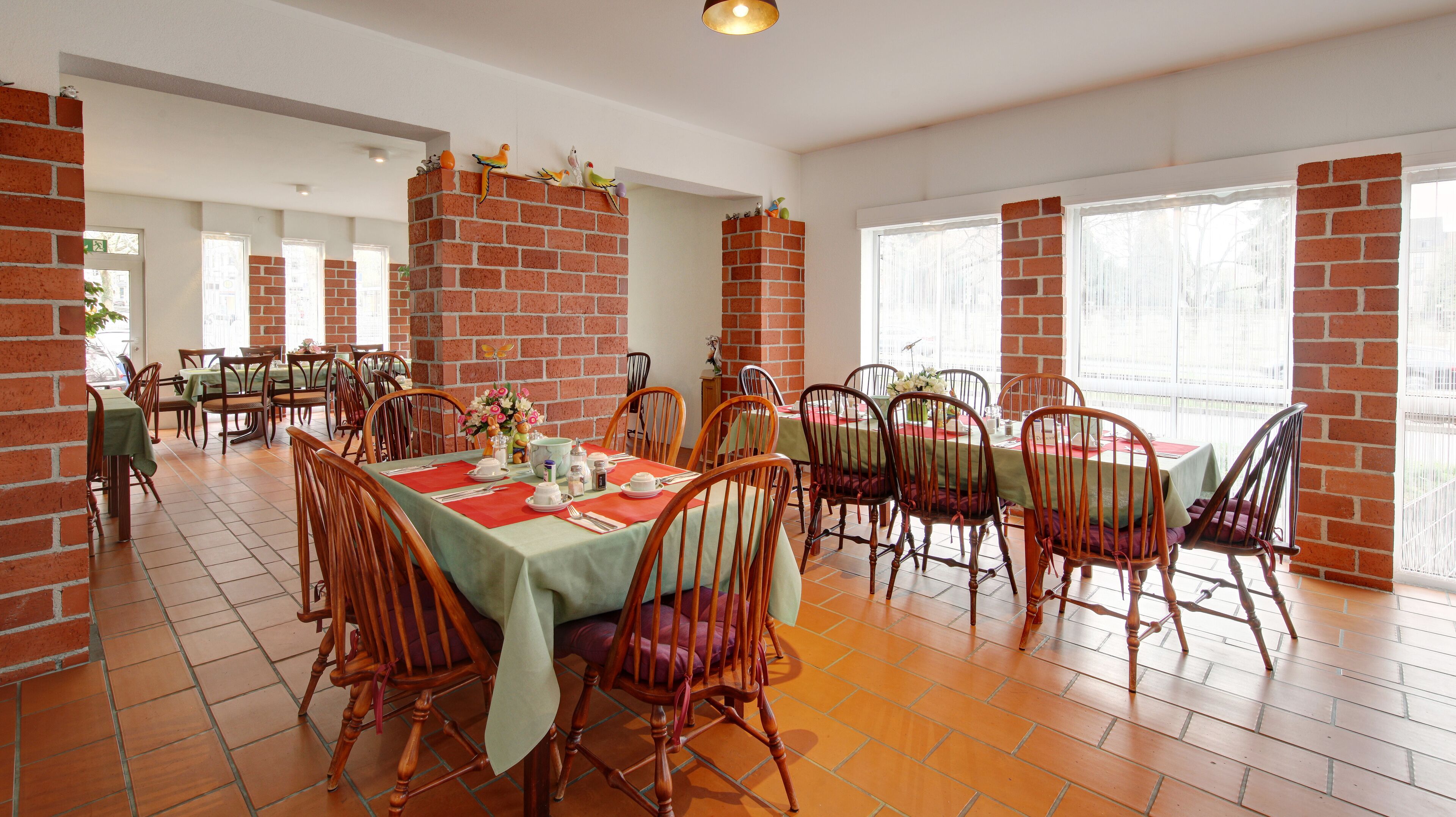 A dining area with brick walls, wooden chairs, and tables set for a meal.