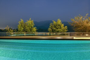 Une piscine à l’eau cristalline, entourée d’arbres et avec des montagnes en toile de fond.