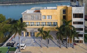 Un bâtiment moderne doté d’un toit plat, de grandes fenêtres et d’un balcon donnant sur une étendue d’eau.