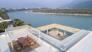 Terraza en la azotea con piscina, zona de comedor y vistas a un río y montañas.