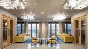 Amplia habitación con dos sofás amarillos, una mesita y grandes ventanales con vistas a la ciudad.