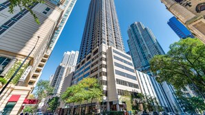 A tall, modern skyscraper with a unique, angular design, surrounded by other high-rise buildings and trees. - LOCATION!!  2b/2b Condo, 51st Floor AMAZING Views, Pool and other Amenities! (Chicago)