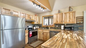 Une cuisine moderne avec des meubles en bois, des appareils en acier inoxydable et un parquet en bois disposé en chevrons.