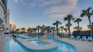 Une piscine avec des chaises longues et des palmiers.