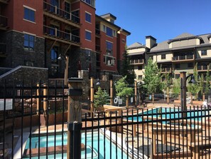 A resort with multiple swimming pools, a stone facade, and a multi-story building with balconies. - 2BR Ski-in-Out Condo with Pool (Park City)