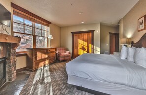 A hotel room with a large bed, a fireplace, a plaid armchair, and a view of the outdoors through the windows. - 2BR Ski-in-Out Condo with Pool (Park City)