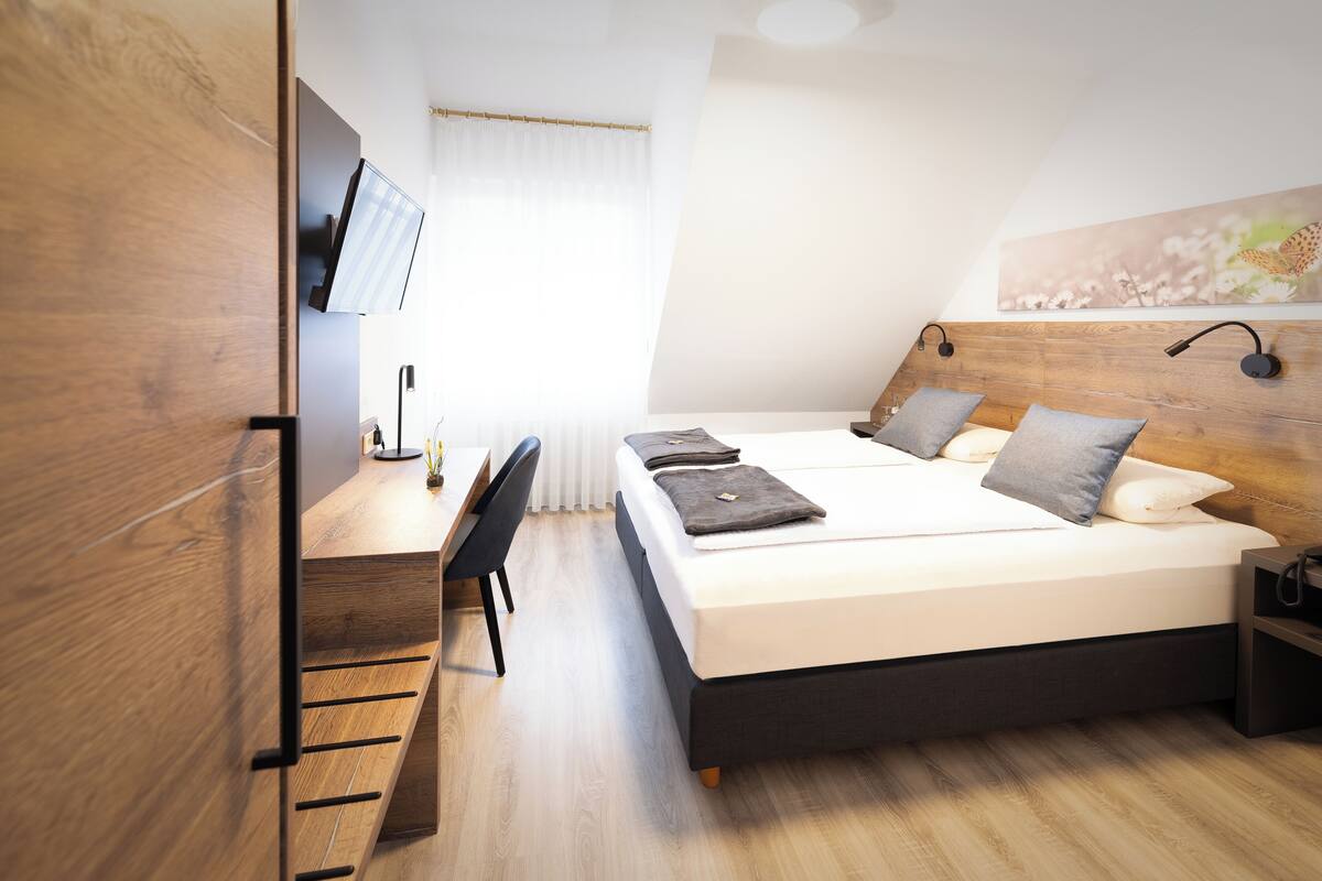 A modern bedroom with a bed, bedside tables, a desk, and a TV.