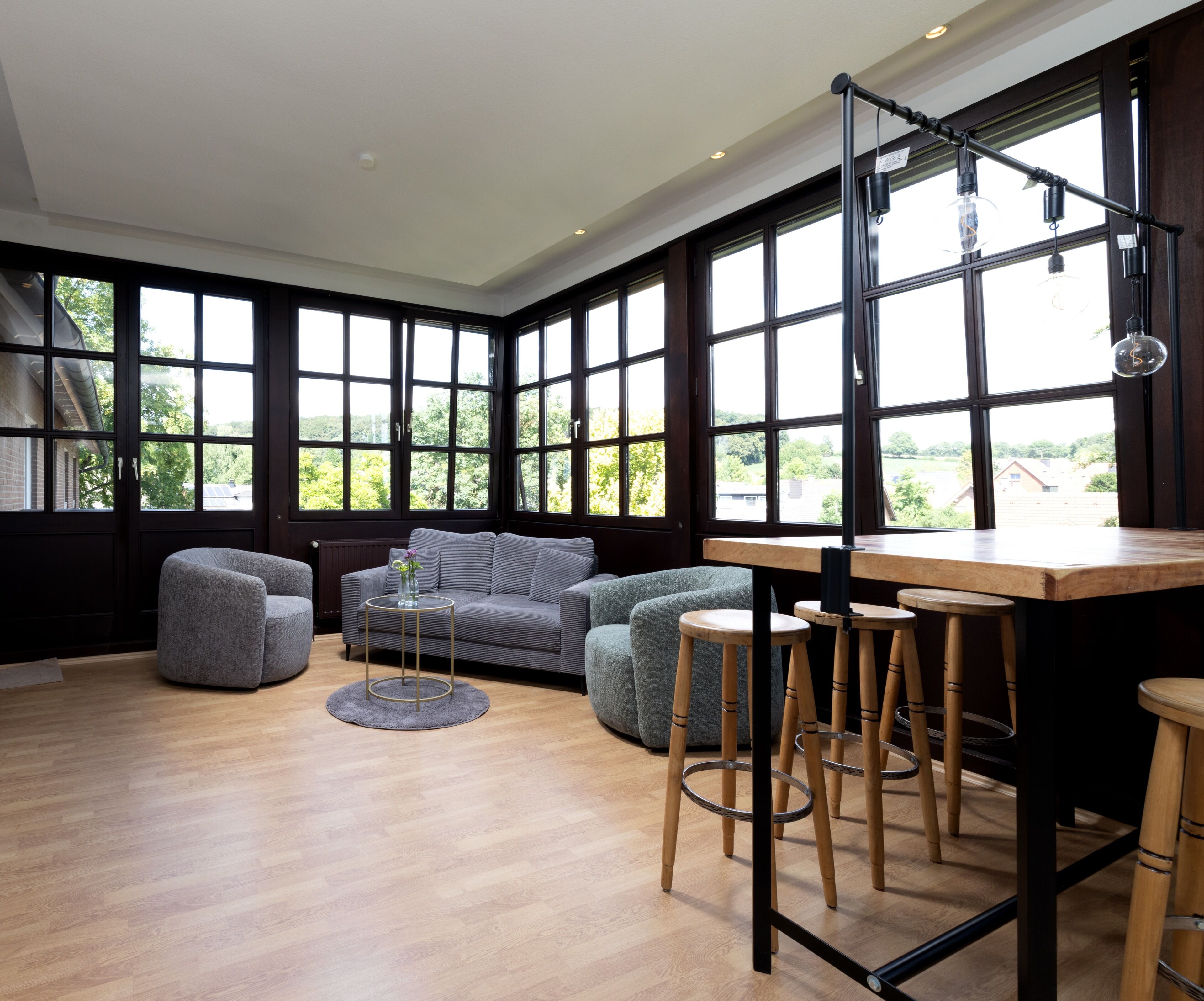 Un intérieur moderne avec de grandes fenêtres, un canapé, une table ronde et des tabourets.