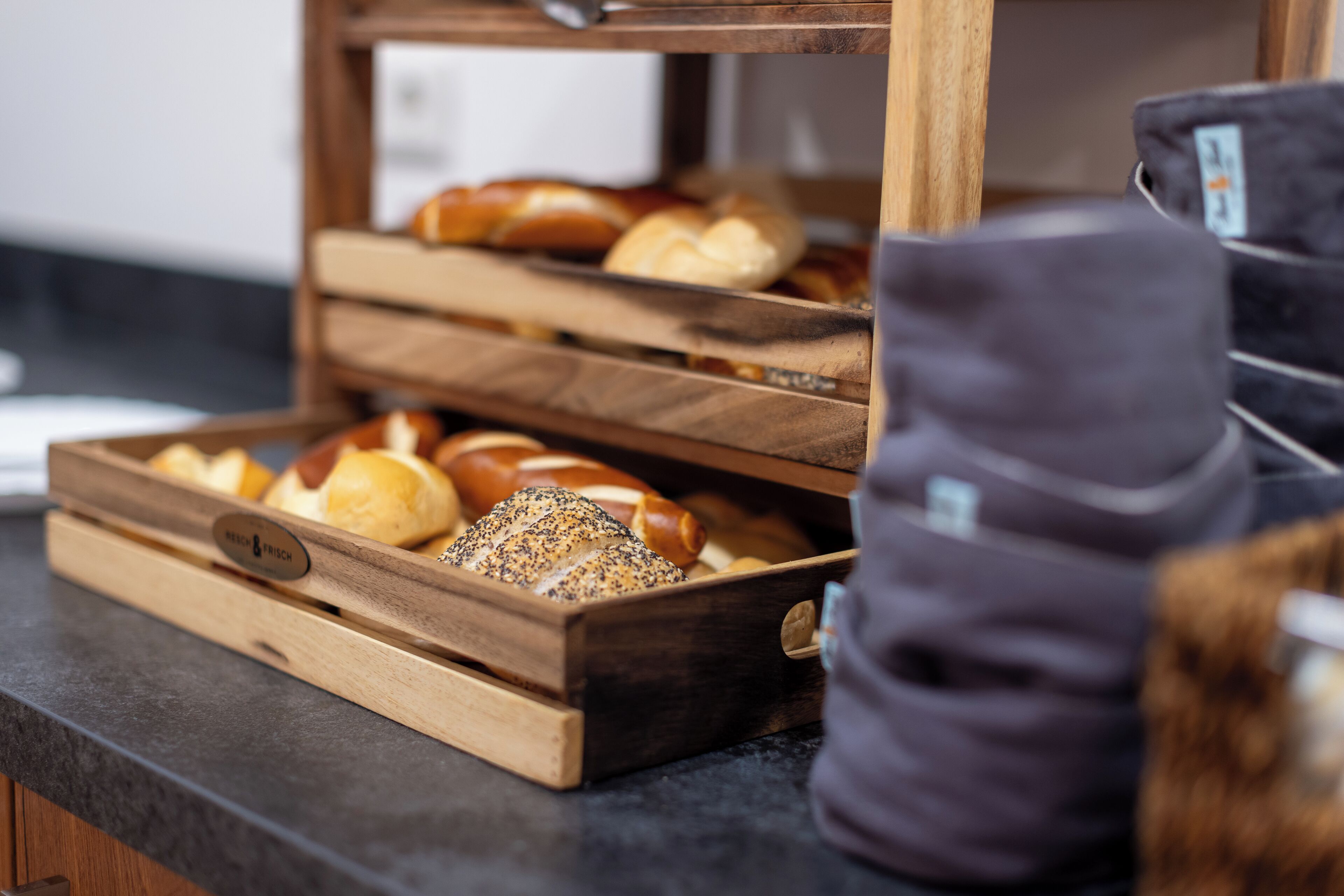 A wooden bread display with various types of bread, including a loaf with seeds.