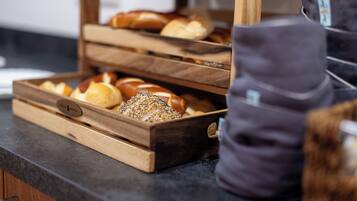 A wooden bread display with various types of bread, including a loaf with seeds.