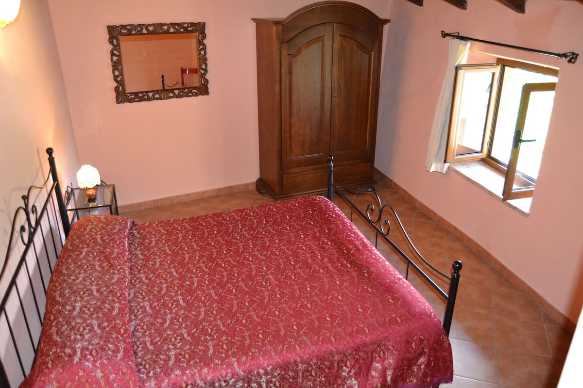 Une chambre à coucher avec un lit, une armoire, un miroir et une fenêtre.