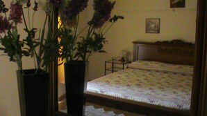 Une chambre à coucher avec un lit, une table de chevet et deux plantes en pot.