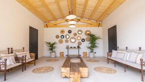A spacious room with a wooden ceiling, a central wooden table, two sofas, and a wall decorated with circular mirrors and potted plants. - Stylish Sicilian Villa with private pool near the Beach. (ispica)