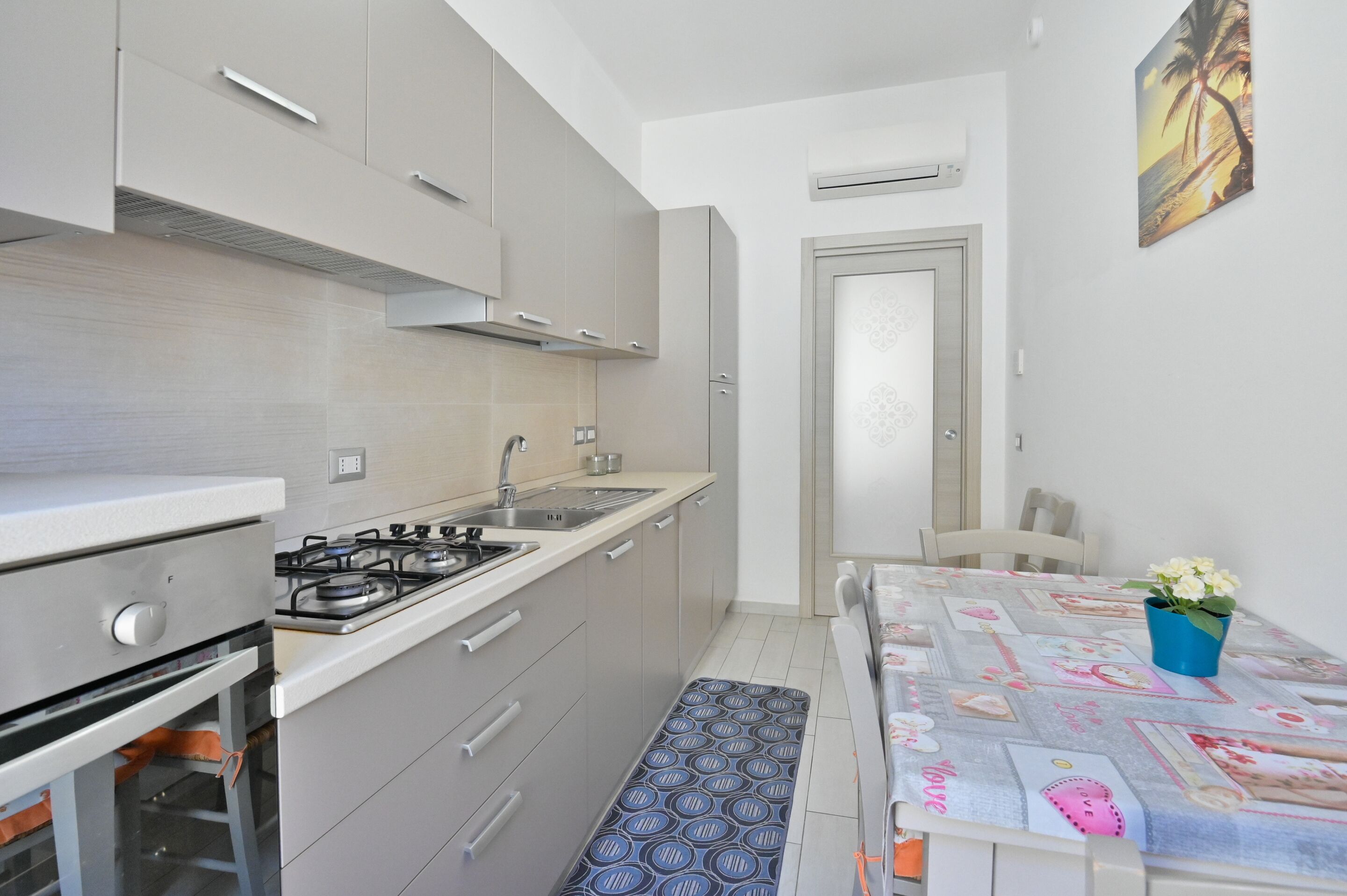 A compact kitchen with a gas stove, sink, and modern cabinetry.