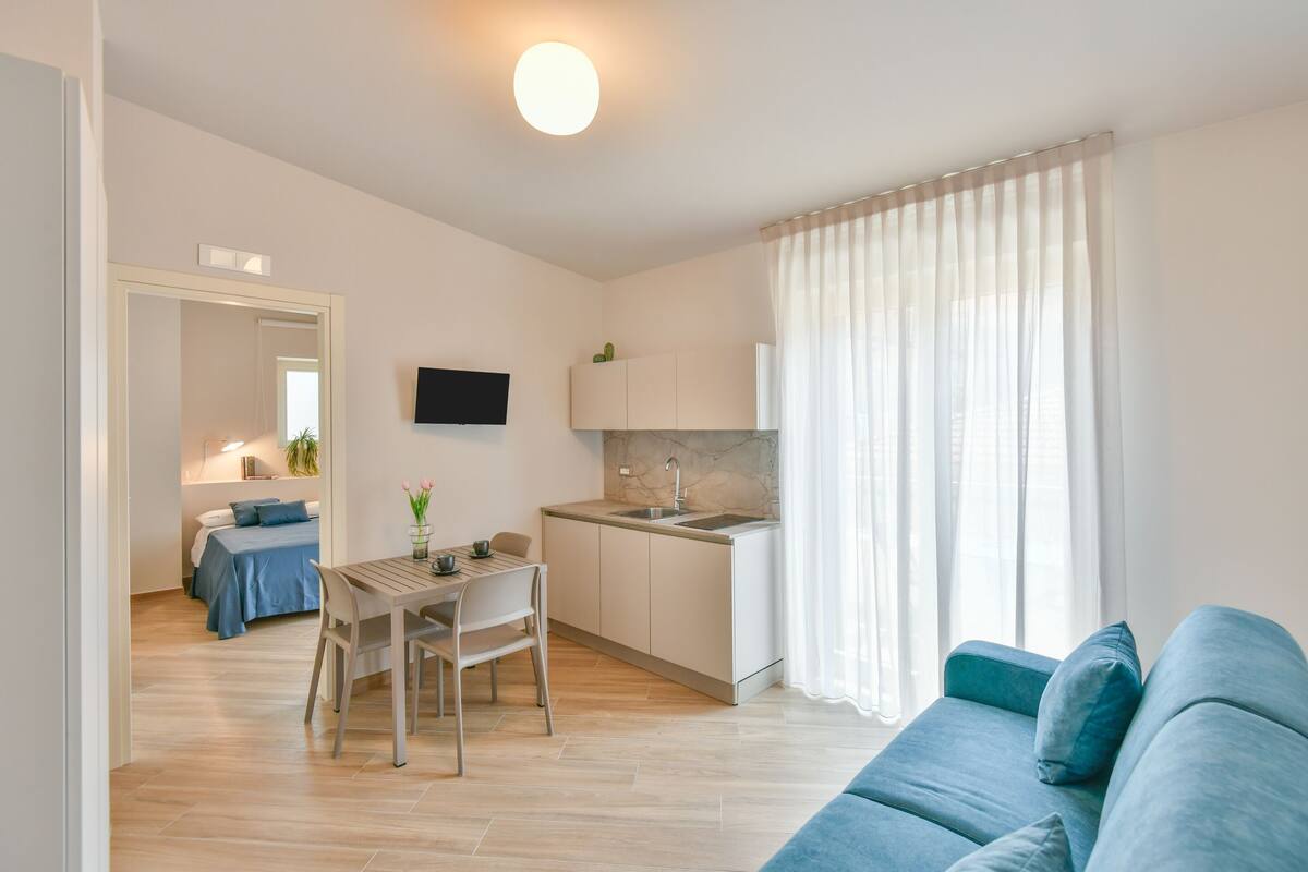 Eine moderne Wohnung mit Essbereich, Küchenzeile und Wohnzimmer mit Sofa.
