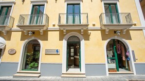 A yellow building with three balconies, a shop entrance, and a sign reading "ODISSEA". - Odissea Residence e Rooms (Castellabate)