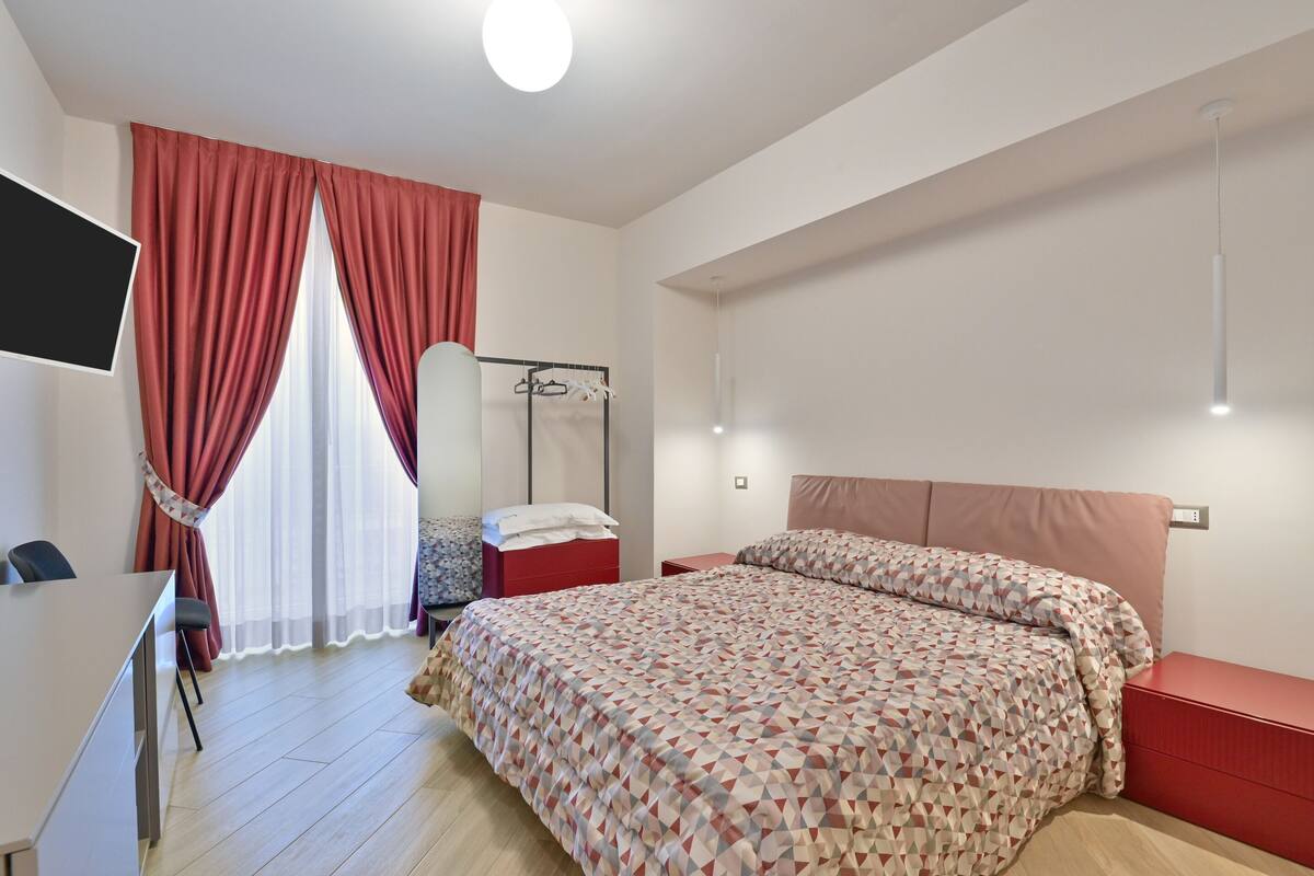 Ein Schlafzimmer mit Bett, Schreibtisch, Stuhl, Kleiderschrank und Spiegel.